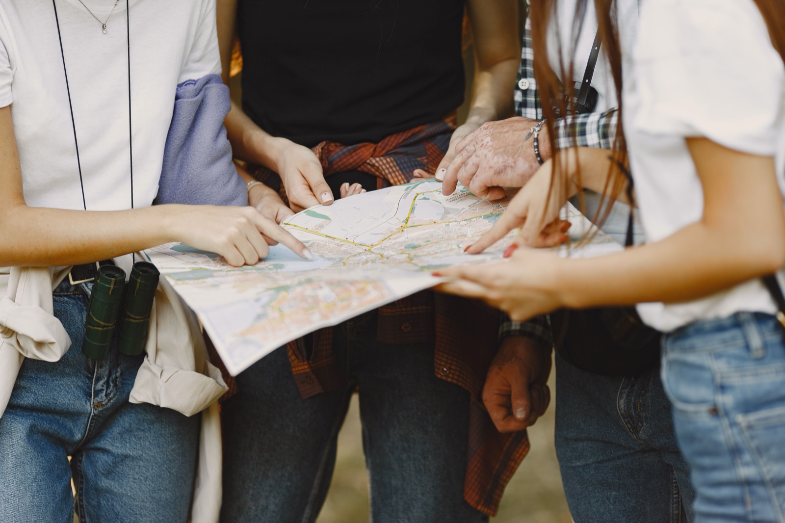 A group of friends pointing at a shared travel map together.